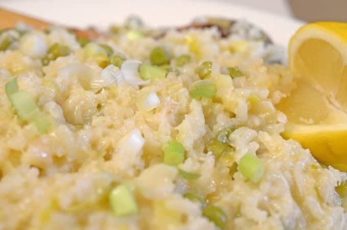 A close up of a plate risotto with peas and other diced vegetables