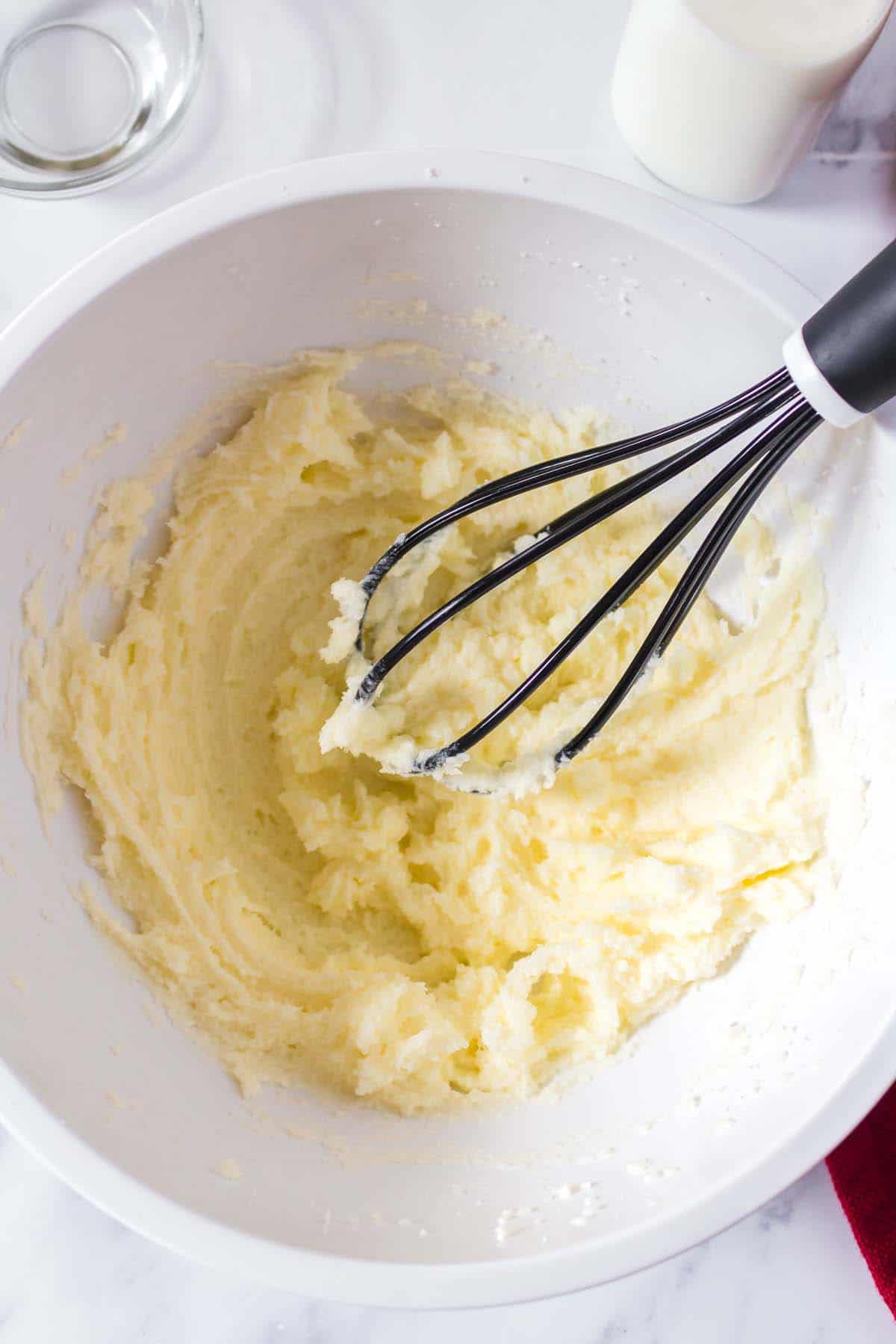 A whisk stirring cookie dough in a mixing bowl.