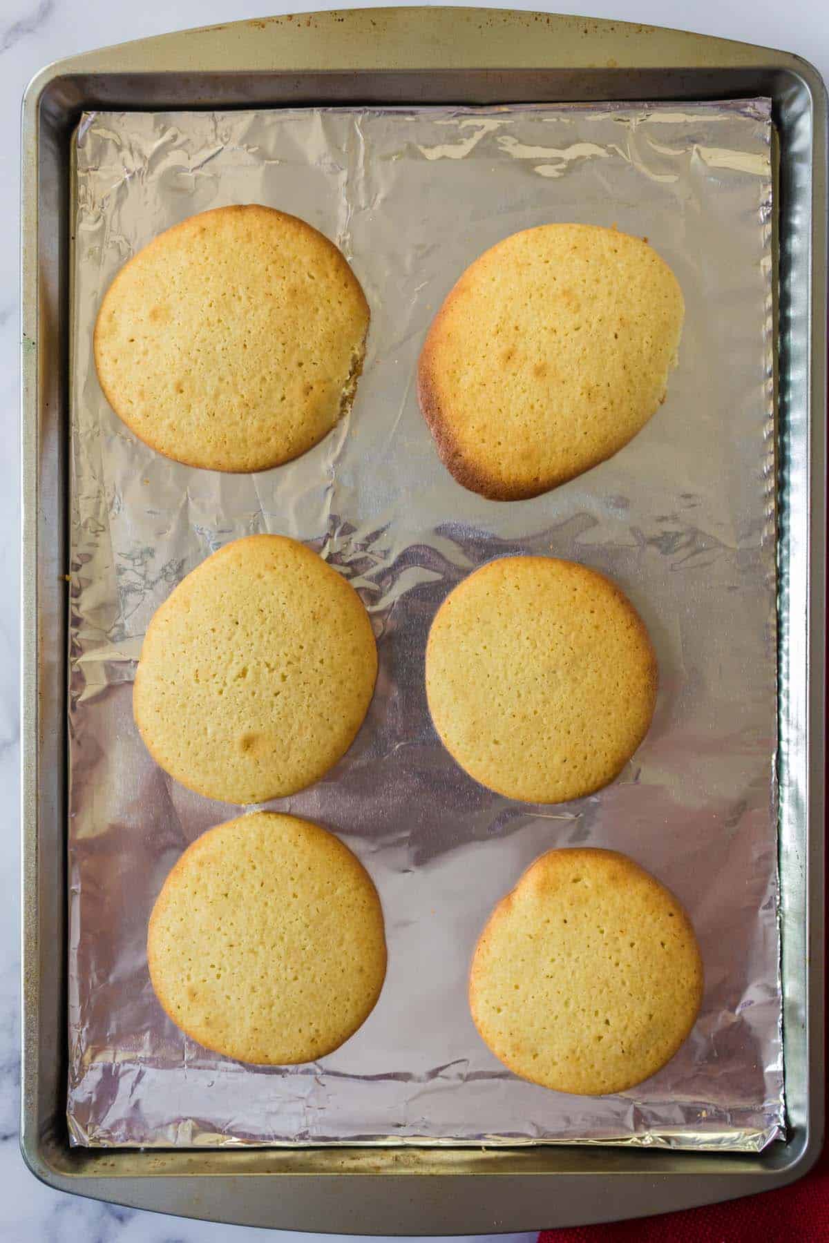 Six baked Amish sugar cookies on a baking sheet.