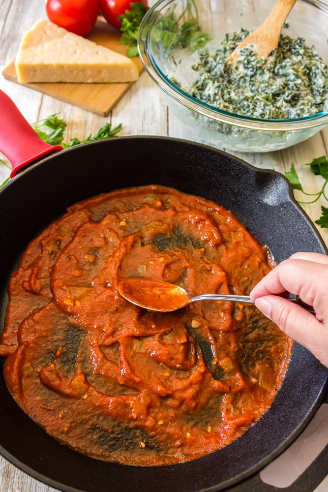 Spreading tomato sauce in the bottome of a skillet.