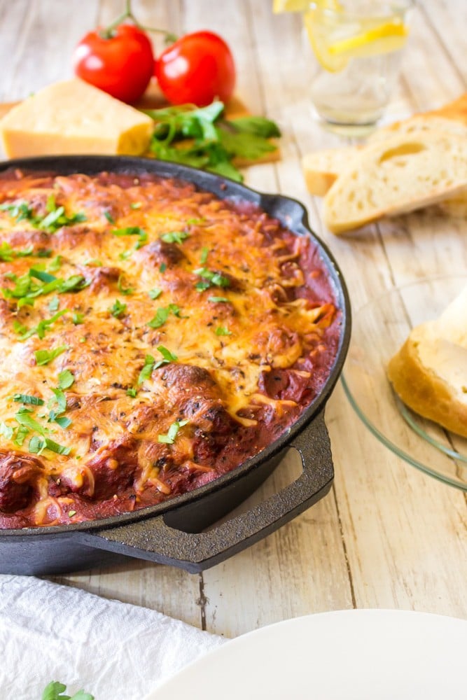 Skillet of lasagna with cheese and bread.