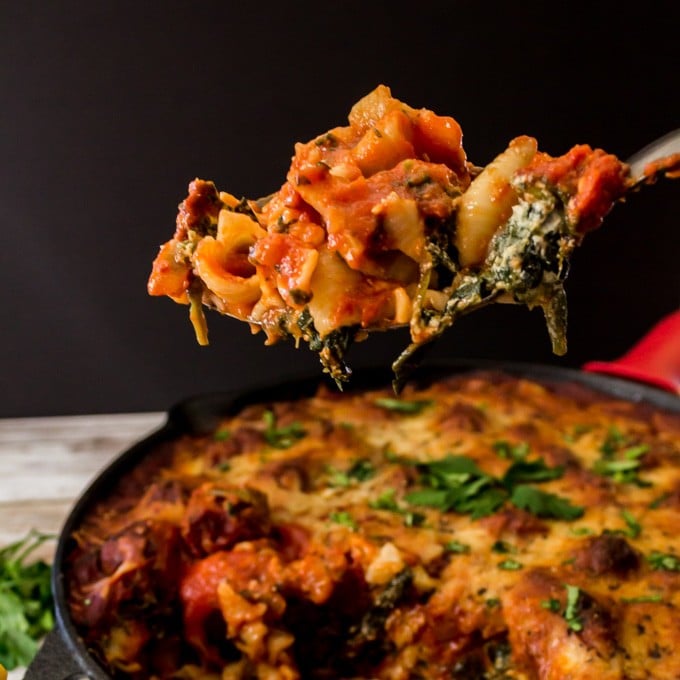 Scoop of lasagna from a cast iron skillet.