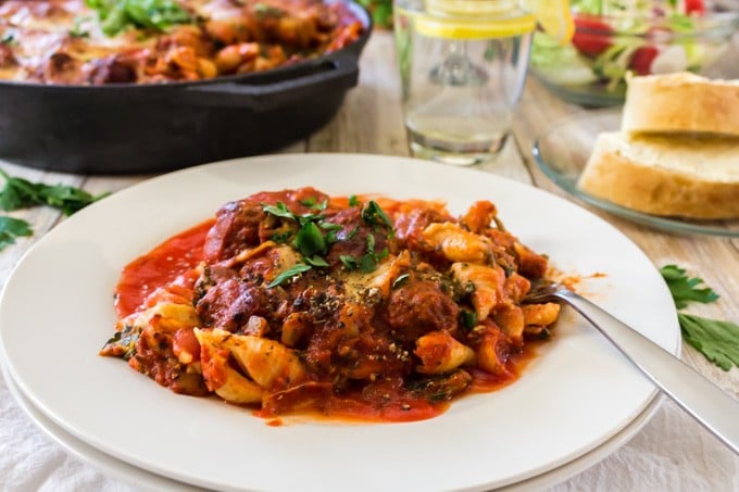 Serving of skillet lasagna with ice water and bread.