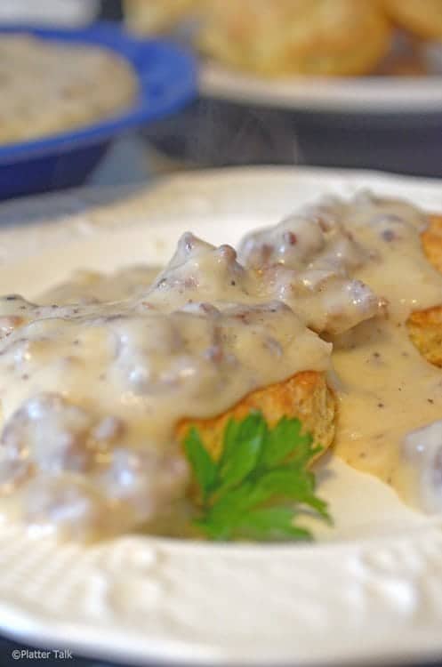 A plate of food, with Gravy and Biscuits