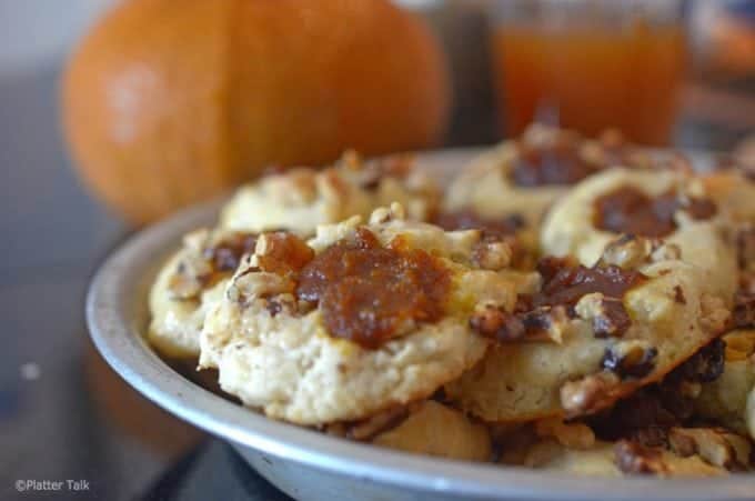 Tray of pumpkin cookies with whole pumpkin in background,