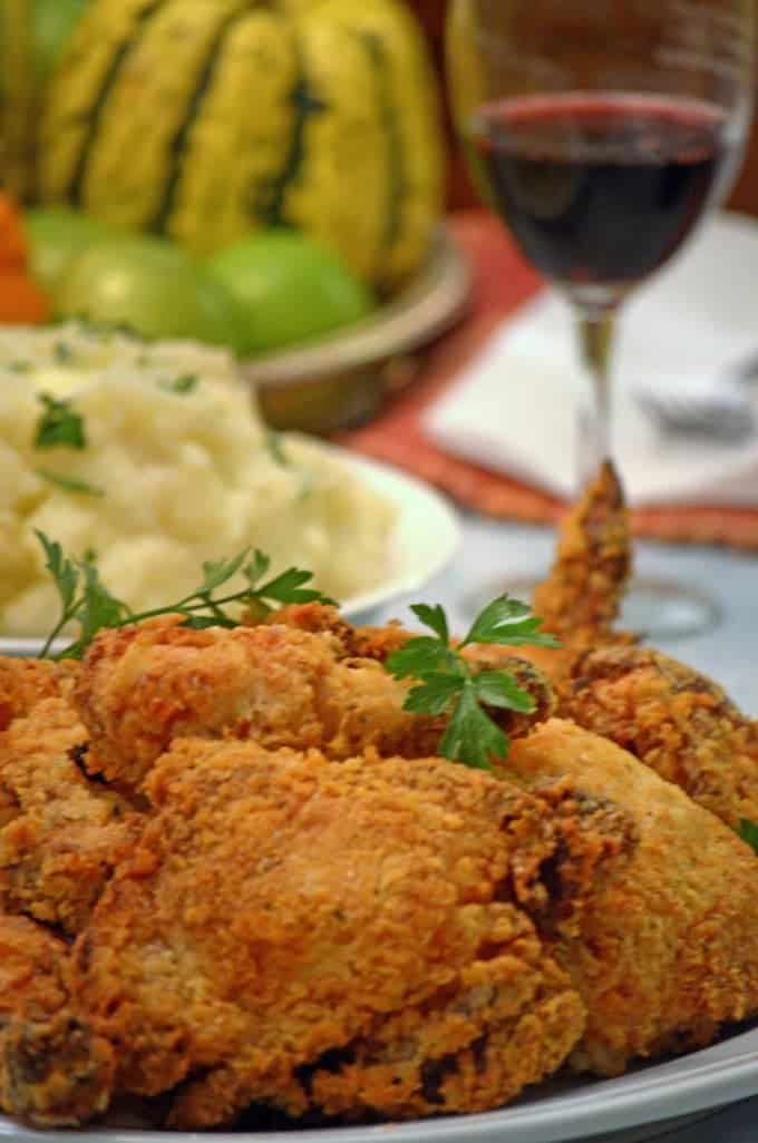 A close up of a plate of food on a table, with fried chicken and mashed potatoes