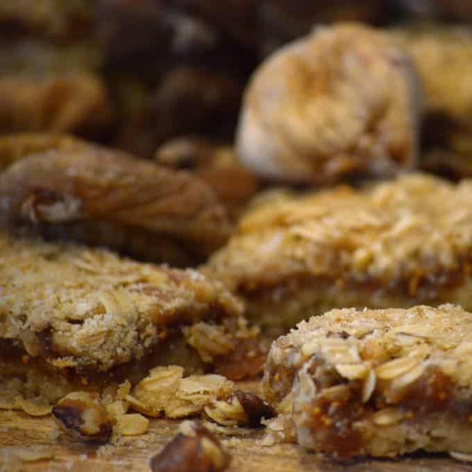 A close up of cut fig bars mixed with whole dried figs on wood
