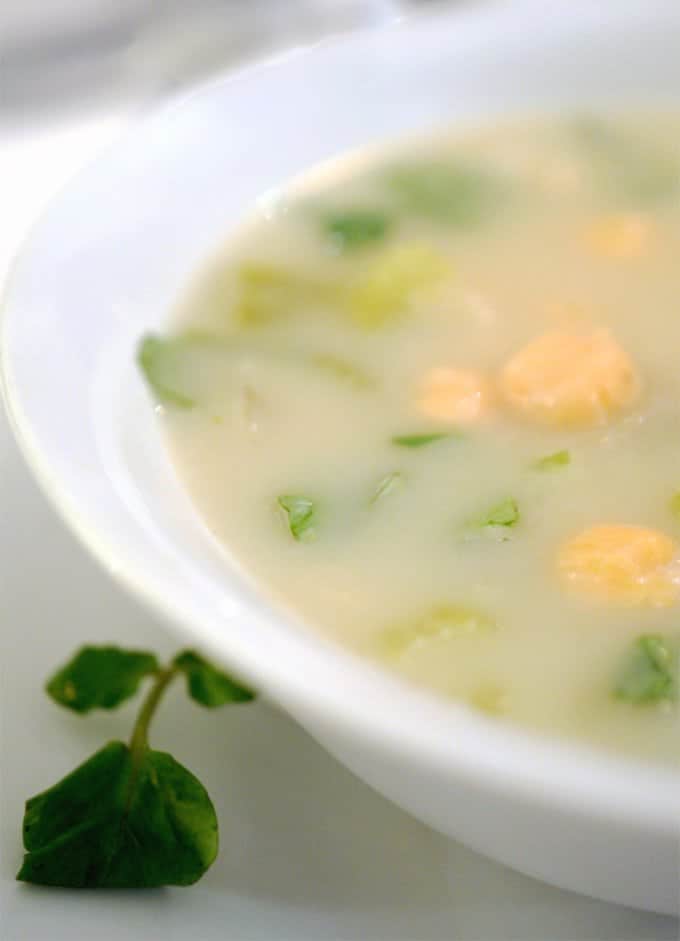 white bowl of fennel soup with watercresss and chickpeas as garnishes,