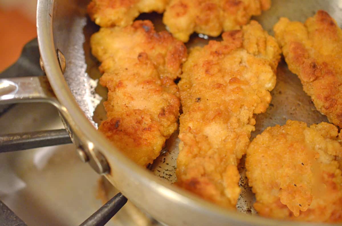 Some crispy chicken strips in a pan.
