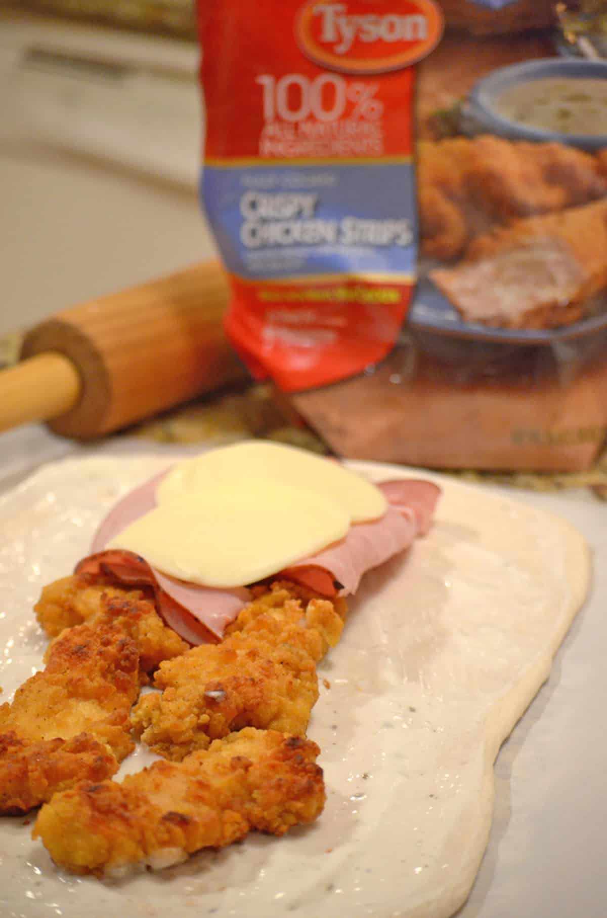 Some piece of crispy chicken on a rolled out dough.