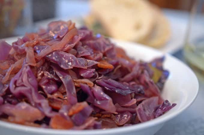 A close up of a bowl of food on a plate, with Cabbage and Platter