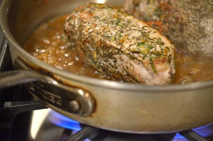 Some meat cooking in a pan.