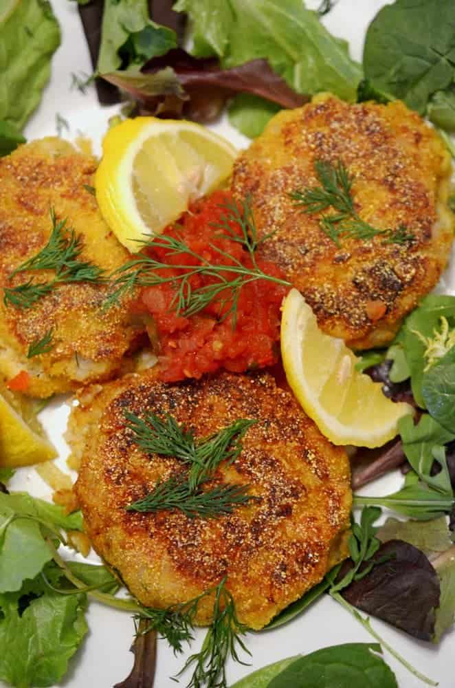 A plate of fish cakes with lemon and dill.