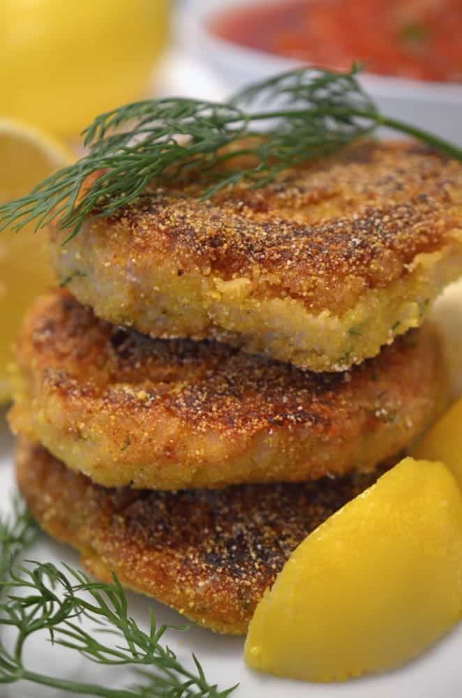 A stack of fish cakes with dill and lemon.