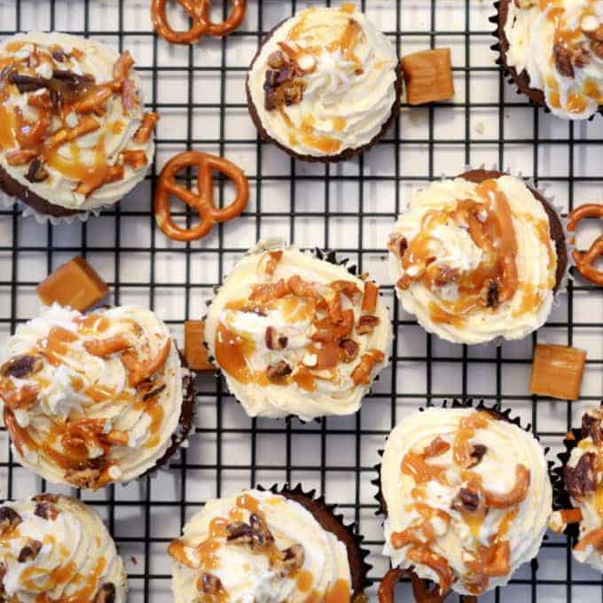 A bunch of cupcakes on a cooling rack.