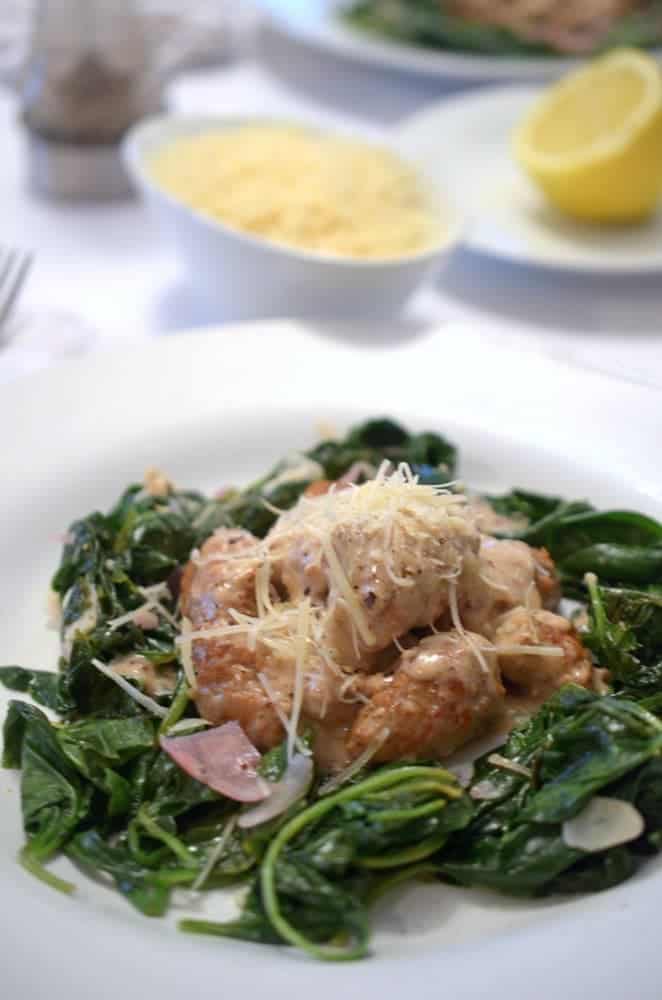 A plate of meat and spinach.