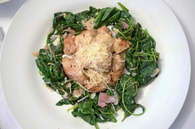 An overhead view of a plate of sausage and cooked spinach.