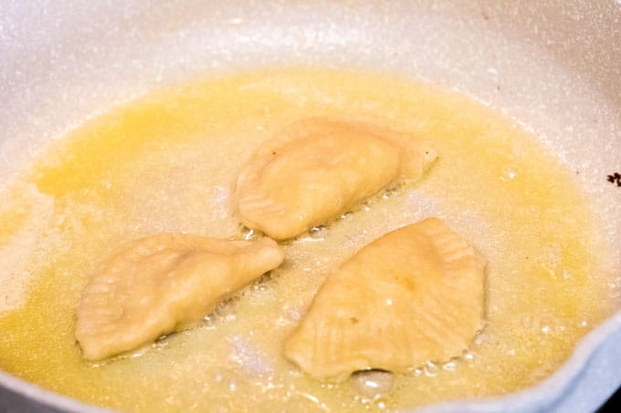 Browning pierogi in a frying pan.