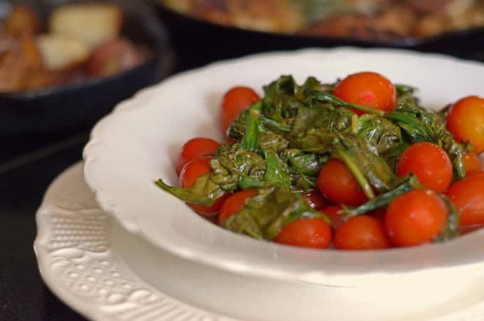 A plate of food on a table with spinach and tomato.