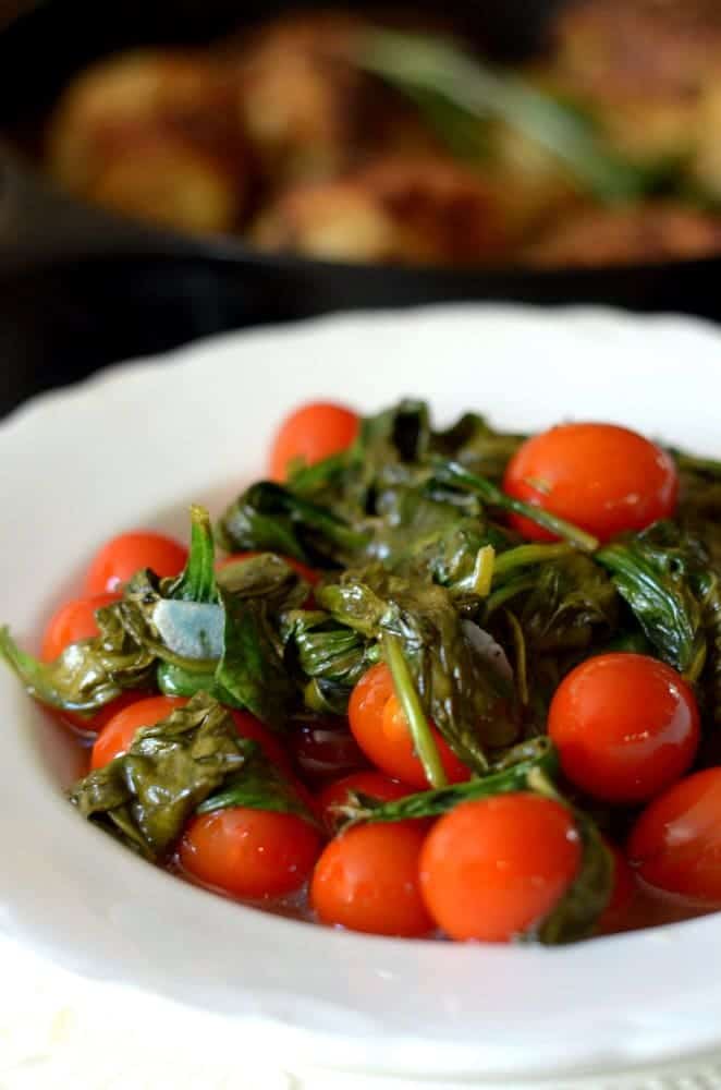 A plate of food with meat and vegetables, with Spinach and Tomato