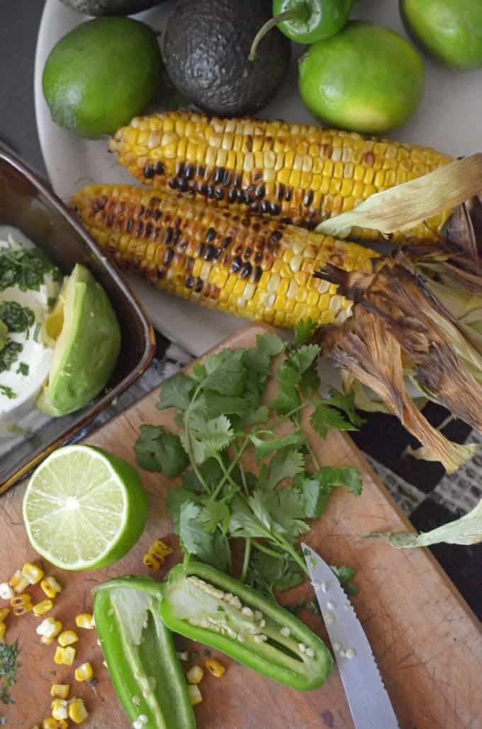 Two charred ears of sweet corn with other vegetables