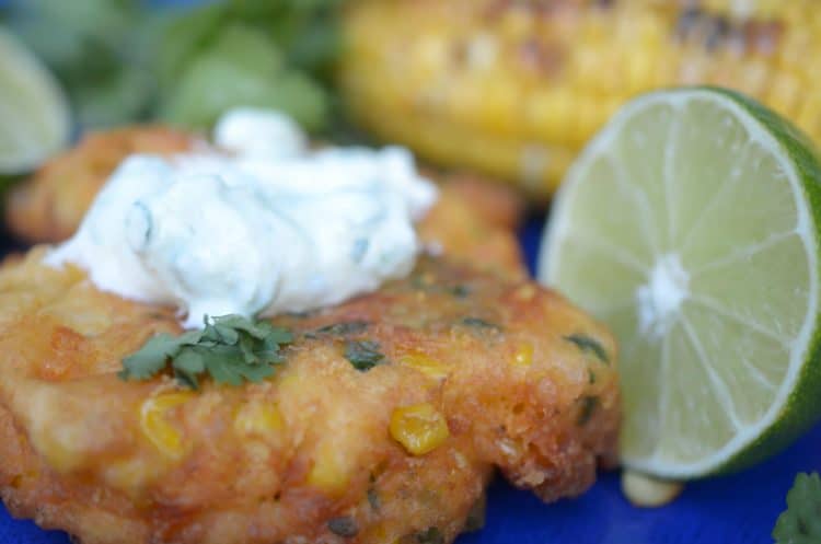 Corn fritter, topped with cream sauce and a half of lime.