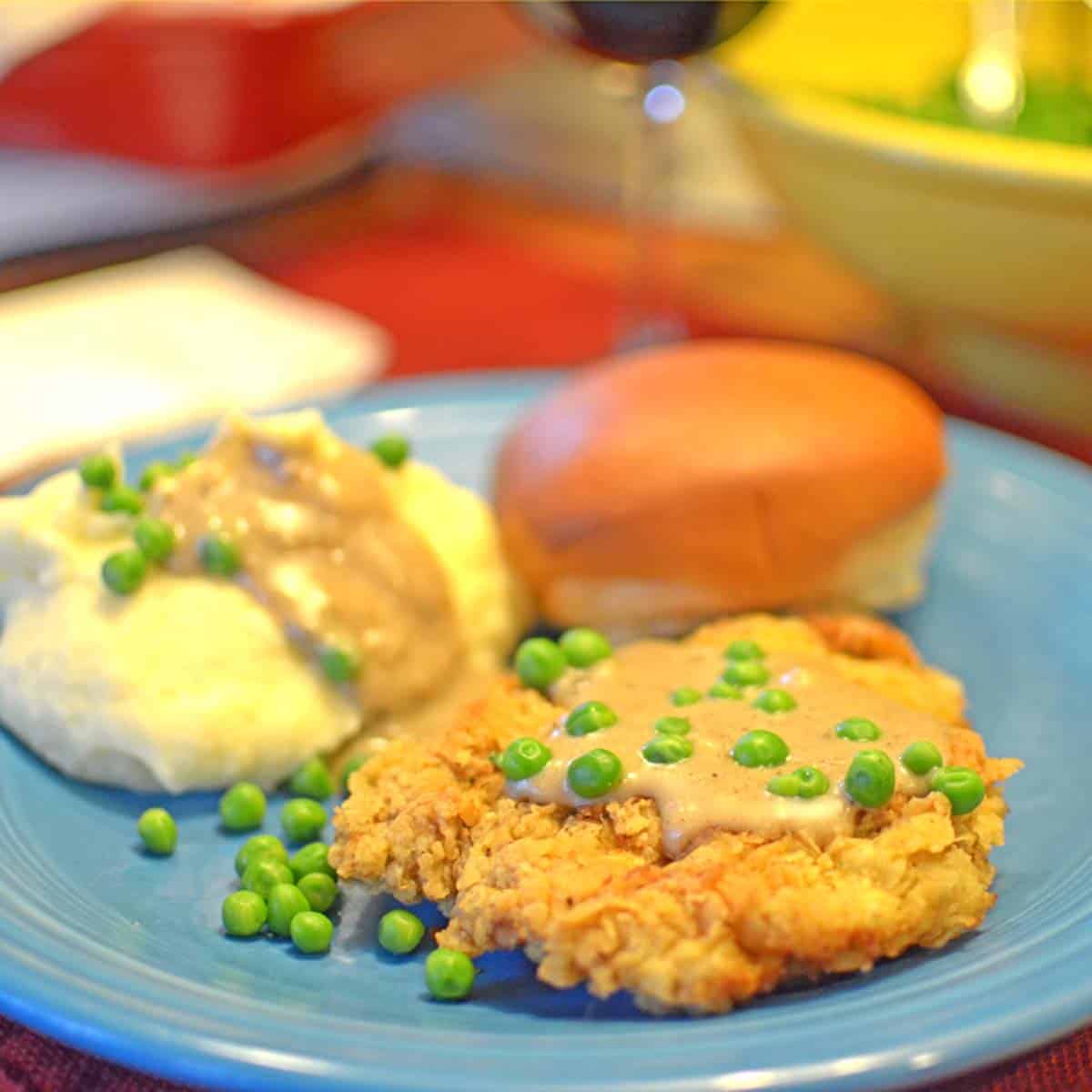 A plate of chicken-fried steak with mashed potatoes and gravy.