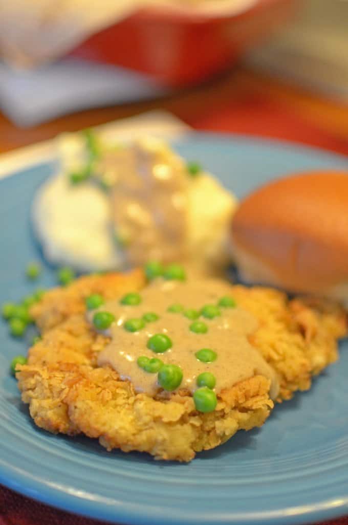 A plate of potatoes, Chicken fried steak, and a roll.