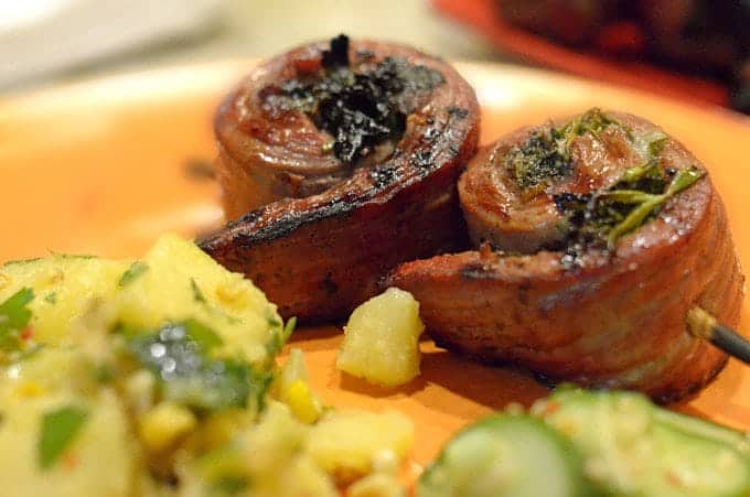 Serving of steak pinwheels on a skewer and plate.