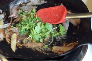A skillet of mushrooms and microgreens.