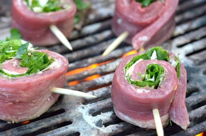 Four portions of beef pinwheels on a hot grill.