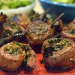 A plate of grilled flank steak pinwheels on a red platter