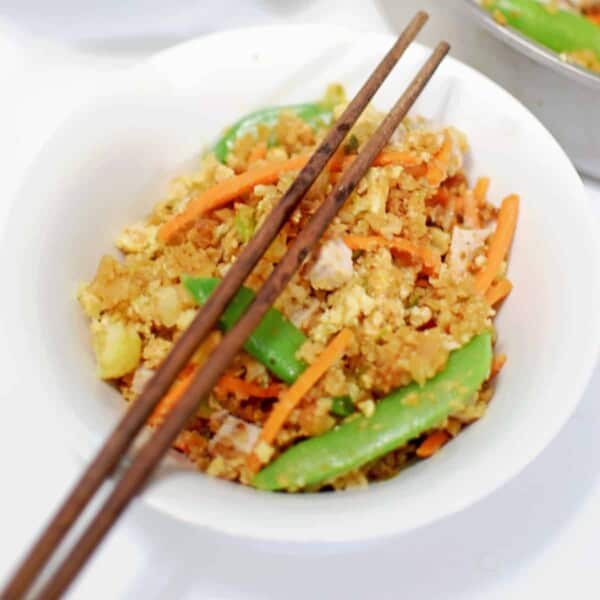 A bowl of fried rice with chop sticks.