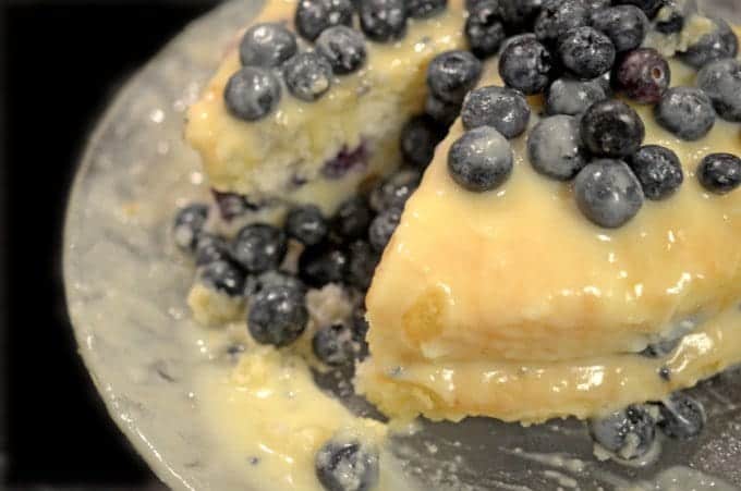 A close up of a blueberry cake with a slice out of it.