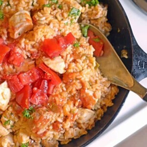 A skillet with a wooden spoon with Jambalaya and Sausage