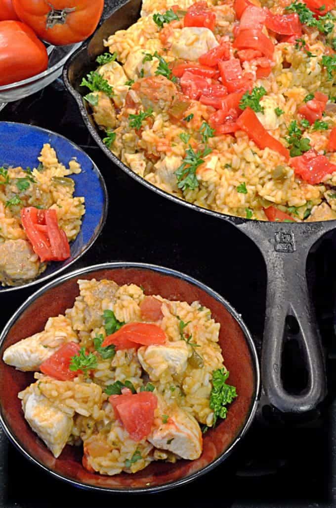 A skillet and two dishes filled with Jambalaya and Chicken