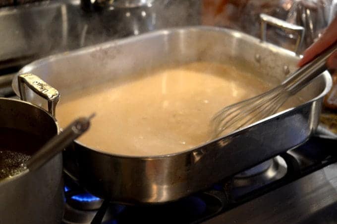 A close up of a metal pan on a stove, making turkey gravy