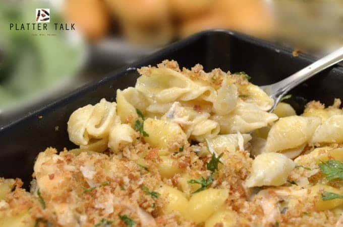 Creamy pasta shells being lifted with fork from dish