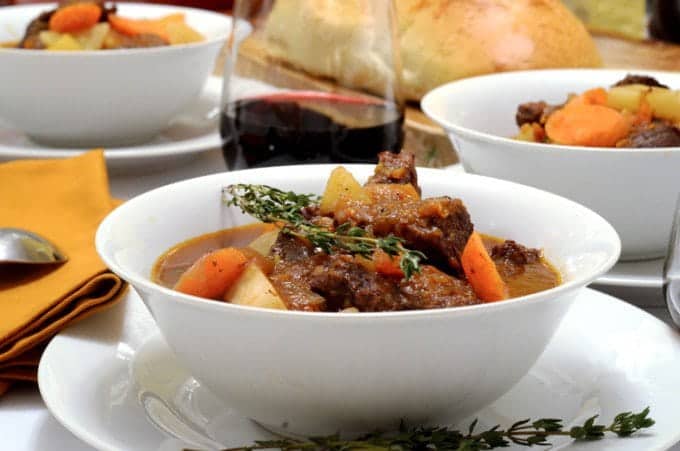 A bowl of food on a table, with Stew and Potato