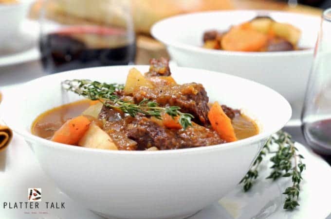 A bowl of food on a plate, with Stew and Carrot