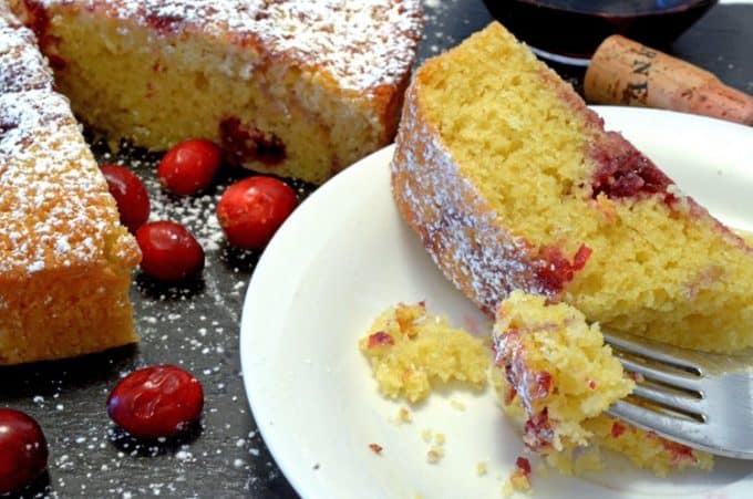 A piece of food on a plate, with cranberries and Cake