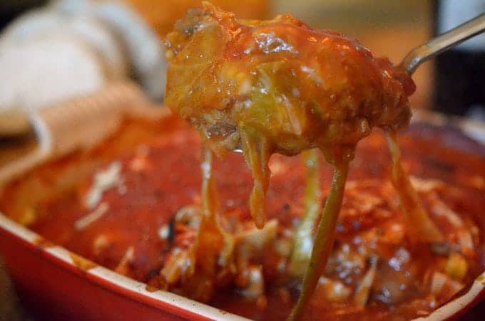 Close up someone removing a cooked cabbage roll from baking vessel