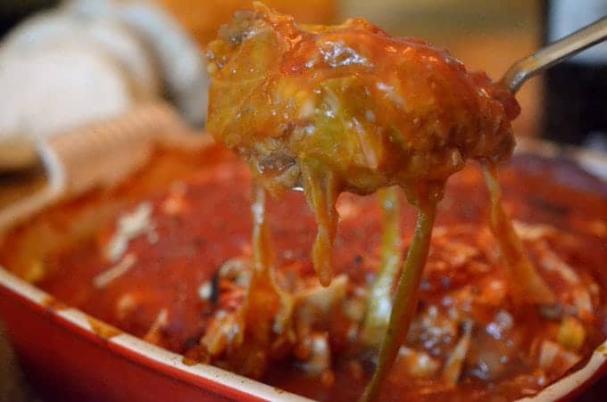 Close up someone removing a cooked cabbage roll from baking vessel 