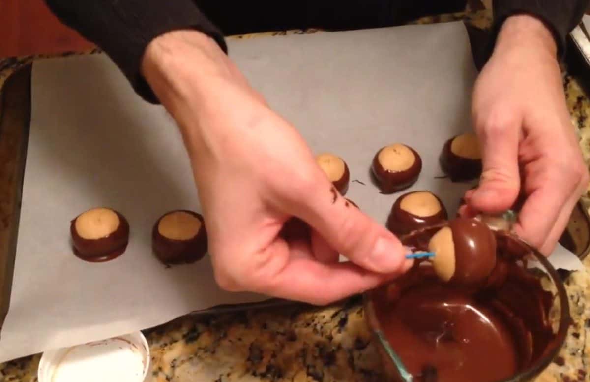 Dipping peanut butter balls into melted chocolate to make buckeyes.