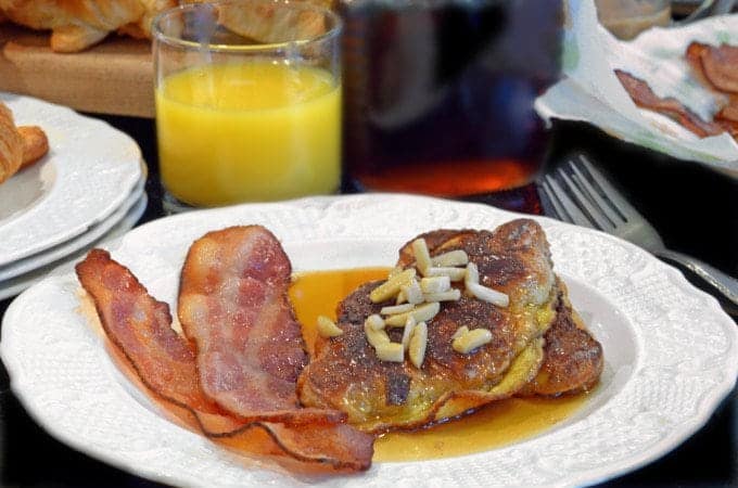 A plate of French toast with bacon and syrup