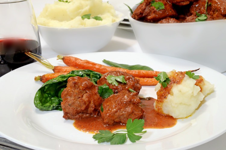 Serivng plate of braised meatballs, carrots, and mashed potatoes.