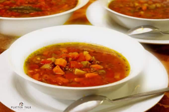 Three bowls of ground beef soup with tomatoes and vegetables.
