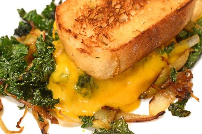 A close up of a plate of food, with Kale  and Cheese Sandwich