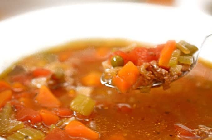 Spoonful of soup with ground beef and vegetables.