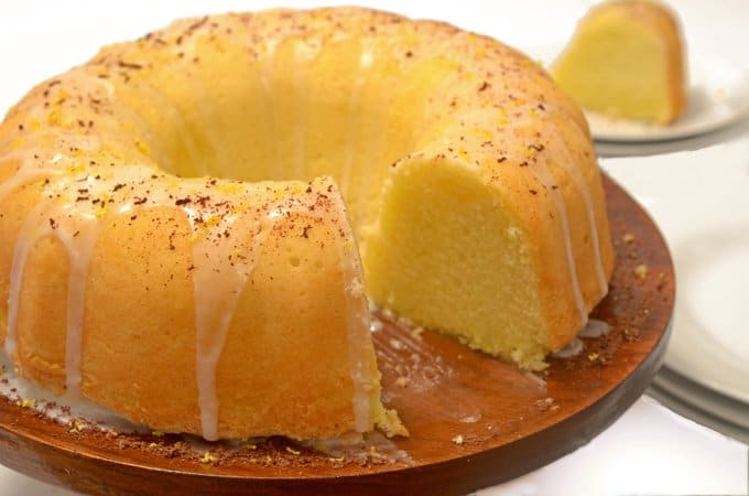 A lemon pound cake on a plate with a piece cut from it